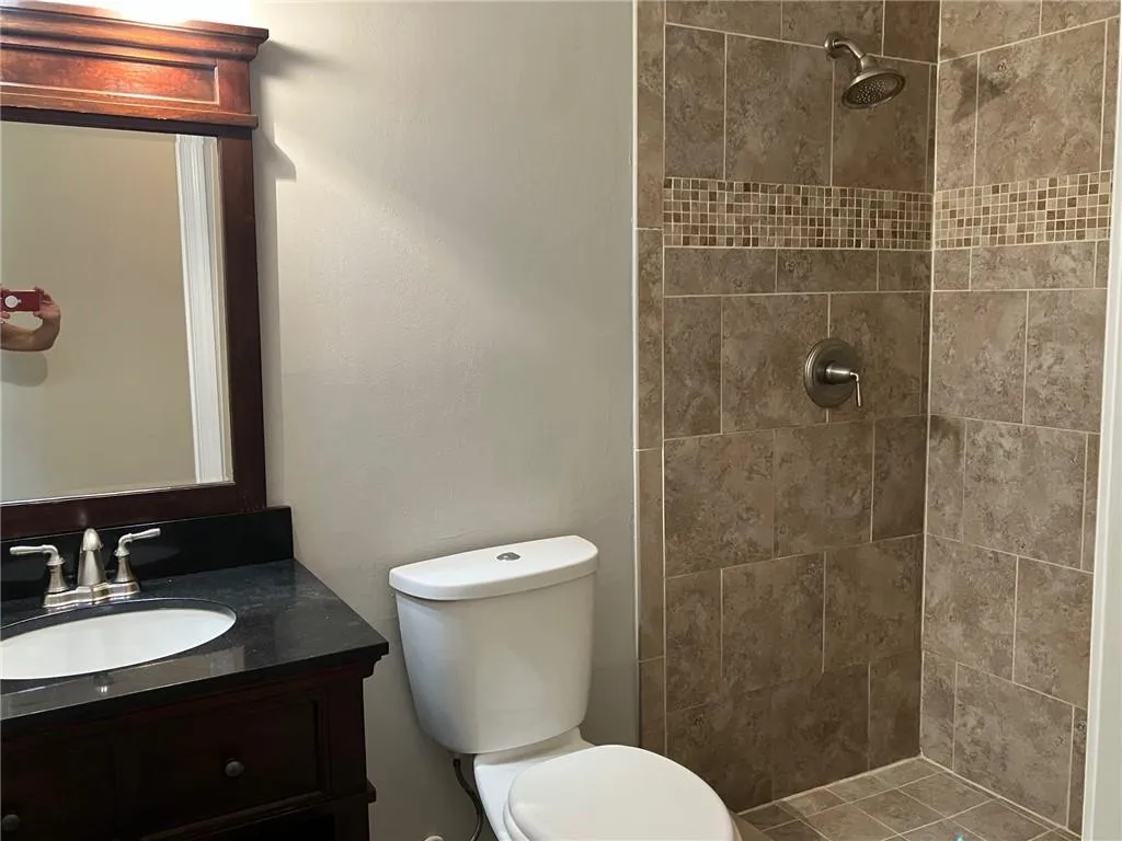 Bathroom with a tile shower, toilet, and large vanity