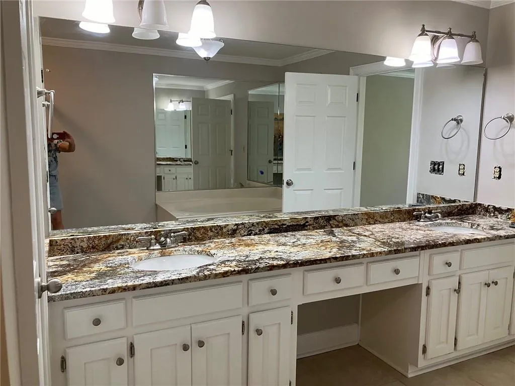 Bathroom with ornamental molding, dual bowl vanity, and tile flooring