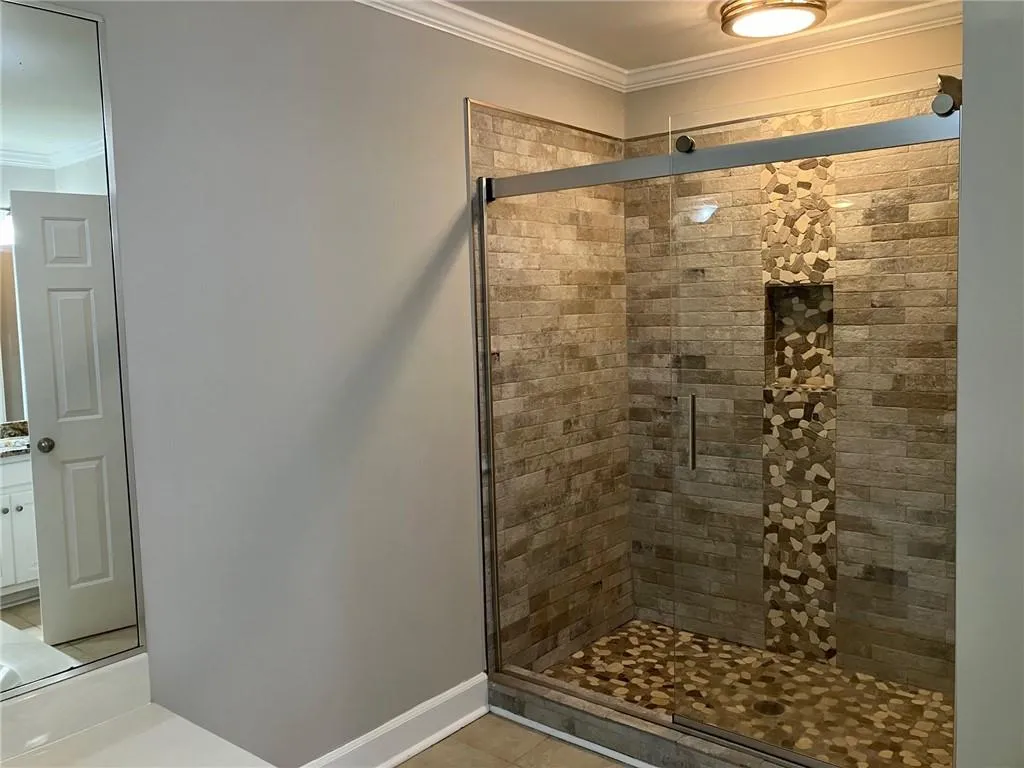 Bathroom featuring crown molding, an enclosed shower, and tile floors