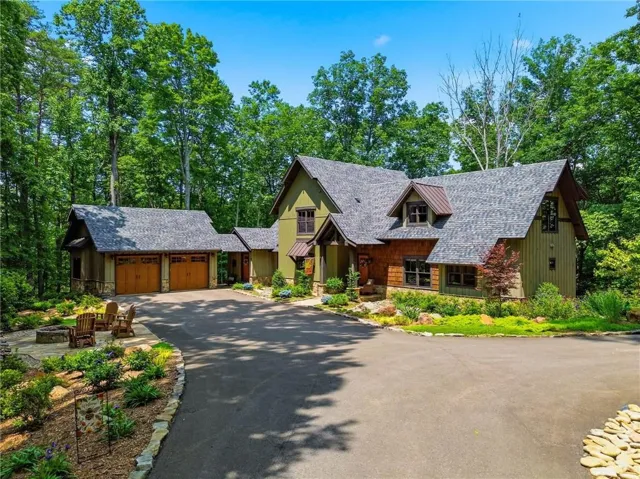 Front exterior featuring timeless mountain architecture, a detached two car garage, lengthy, paved driveway, and professional landscaping.