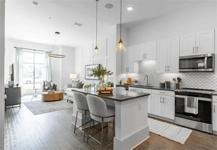 Kitchen featuring stainless steel appliances, dark stone counters, a center island, white cabinets, and open floor plan