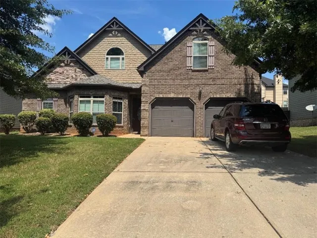 Brick and shingle exterior with bay window, arched window, and two-car garage