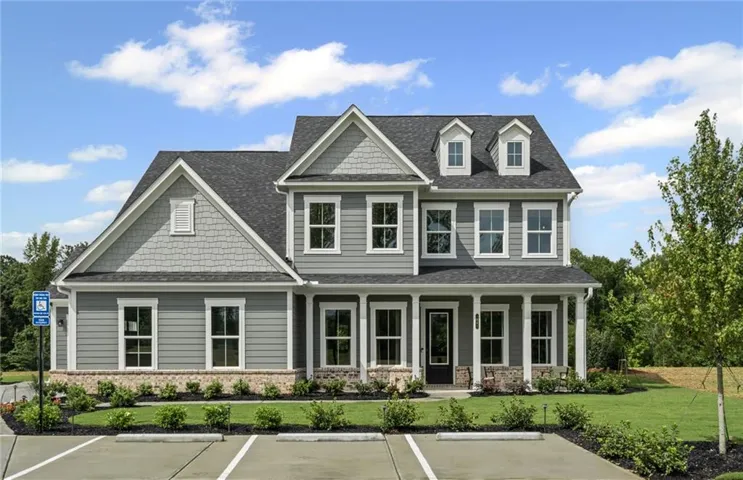 Two-story residence featuring gray siding with complementary shake accents, a dark shingle roof, and a welcoming front porch
