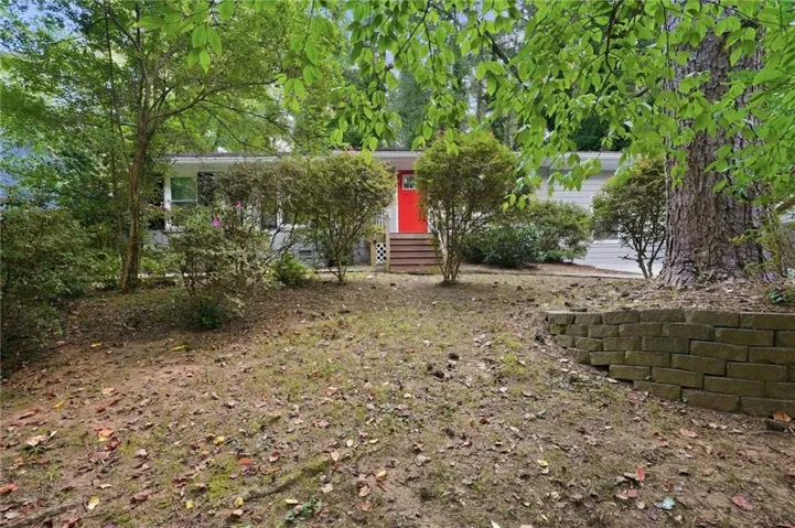 Single-story residence featuring a vibrant red front door, wood steps, and a white exterior