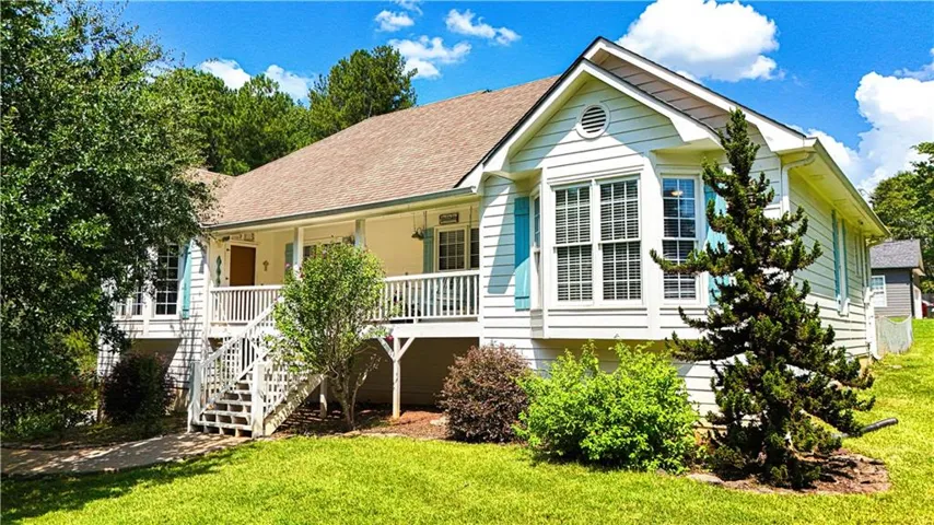 Elevated white siding exterior with a covered porch, bay window, and light blue shutters