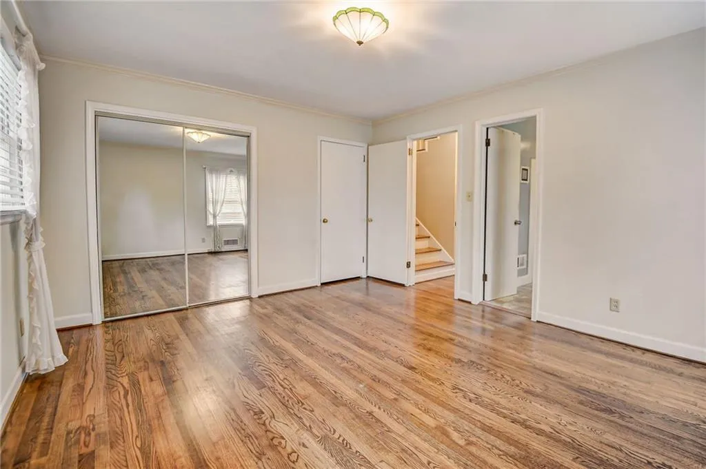 Unfurnished bedroom featuring ensuite bathroom, light hardwood / wood-style flooring, and ornamental molding