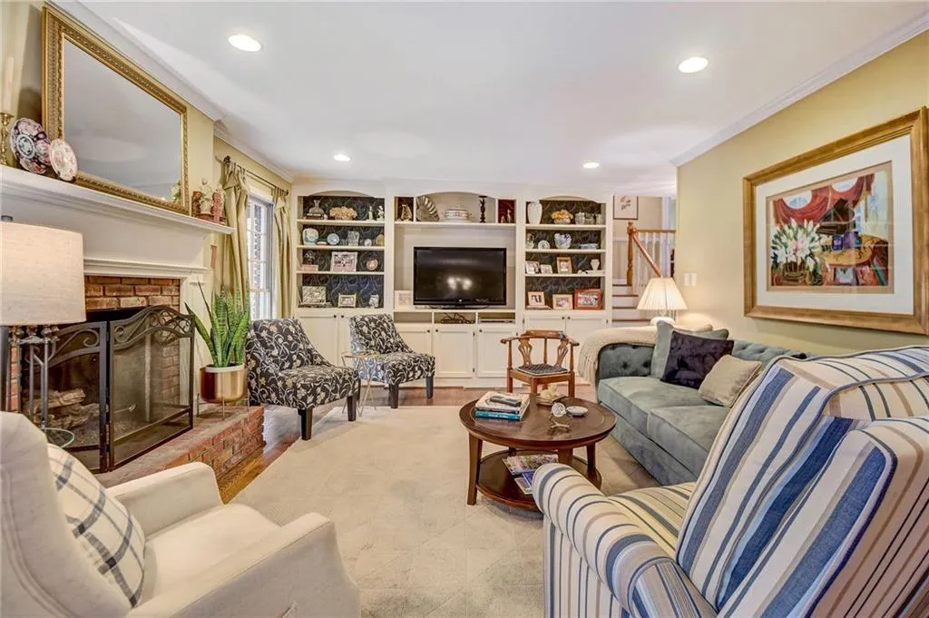 Living room with a brick fireplace, ornamental molding, and built in features