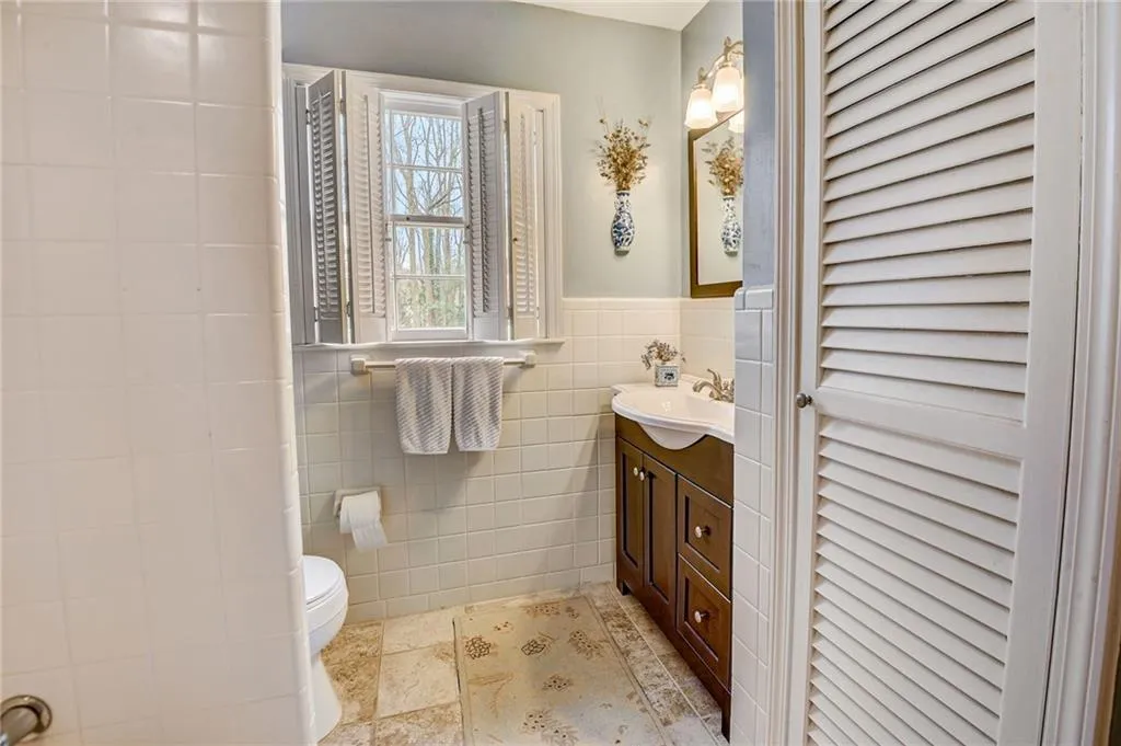 Bathroom with tile walls, vanity, toilet, and tile floors