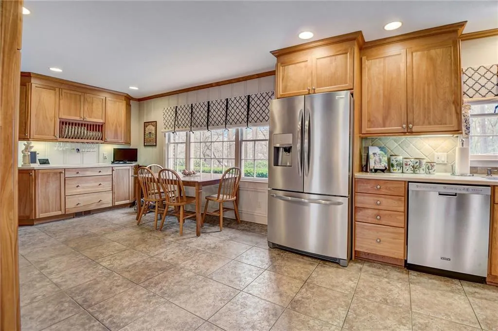 Kitchen featuring a wealth of natural light, light tile floors, stainless steel appliances, and crown molding