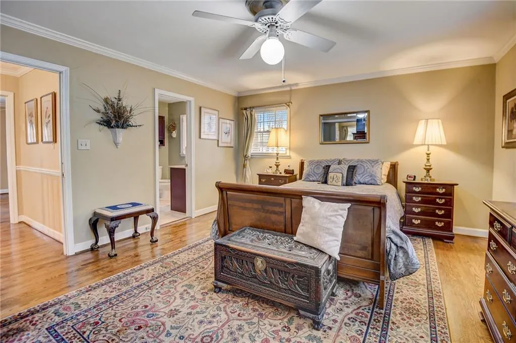 Bedroom with ensuite bath, ornamental molding, ceiling fan, and light hardwood / wood-style floors