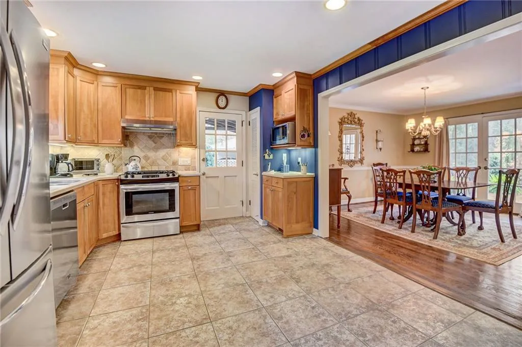 Kitchen featuring appliances with stainless steel finishes, an inviting chandelier, a wealth of natural light, and light tile flooring