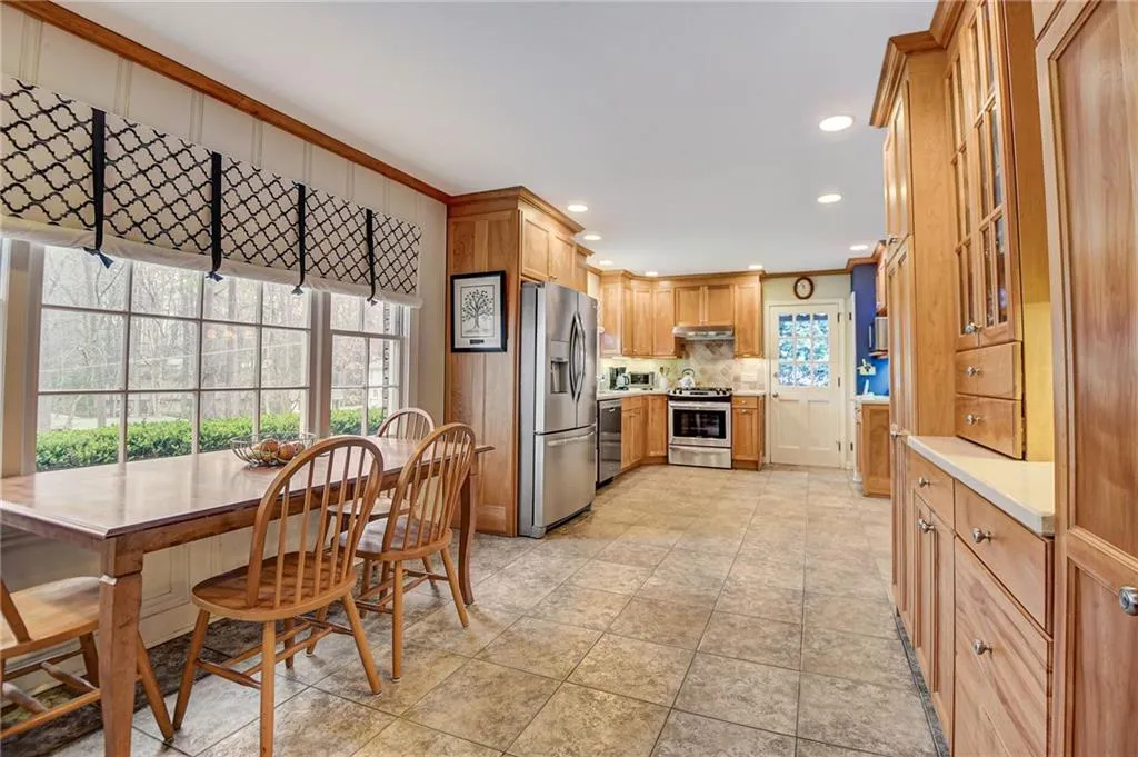Kitchen with backsplash, light tile flooring, stainless steel appliances, and crown molding