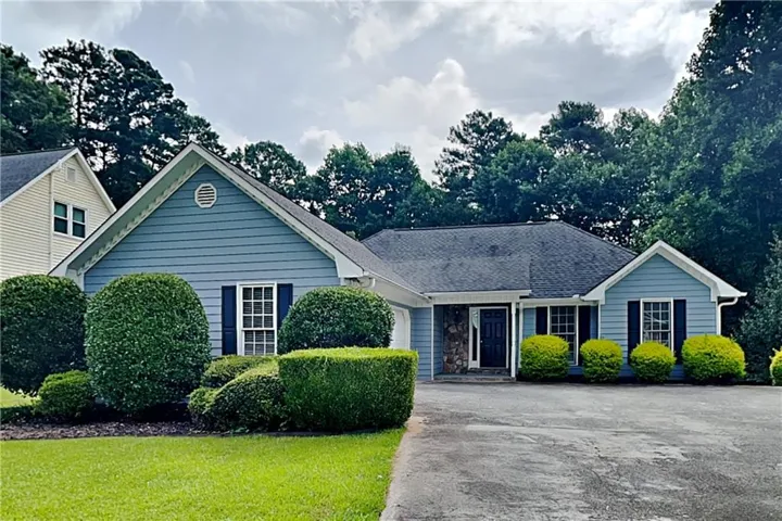 Ranch-style exterior featuring blue siding, dark shutters, and a stone accent entryway