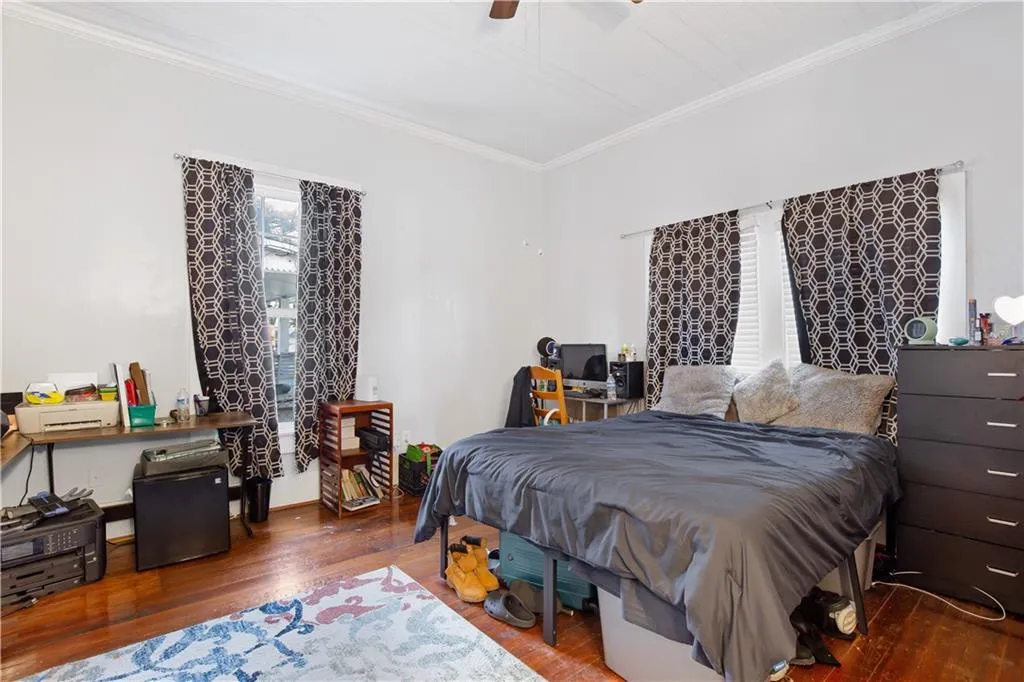Bedroom featuring crown molding, dark wood-type flooring, and ceiling fan