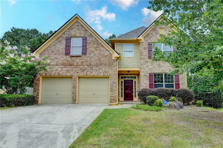 Brick exterior with gabled roof lines, prominent two-car garage, and mature landscaping