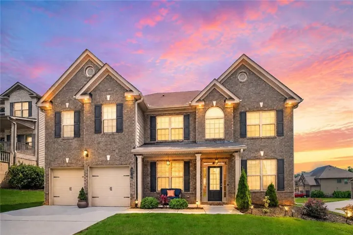 Brick facade residence featuring a covered entry porch, two-car garage, multiple gabled rooflines, and a landscaped front yard