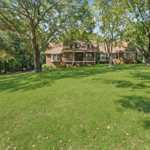 Brick exterior with a covered front porch featuring white railings, multiple dormer windows, and bay windows