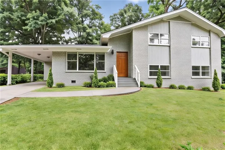 Mid-century modern residence featuring a light brick exterior and a covered carport