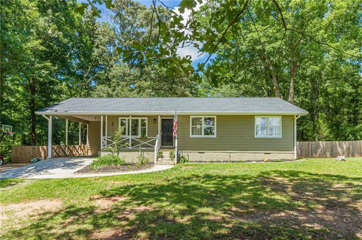 Ranch-style residence featuring horizontal siding, a covered porch, and a paved driveway leading to a carport