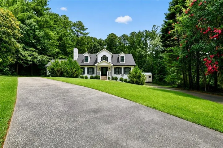 White colonial-style home with a dark shingle roof, black shutters, and a prominent front porch