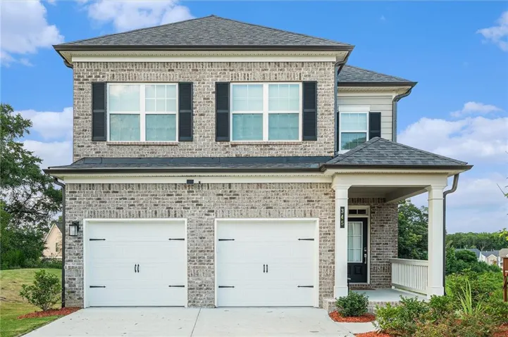 Brick exterior, dual garage doors with decorative hardware, front porch with columns, dark-framed windows with exterior shutters, and a shingle roof