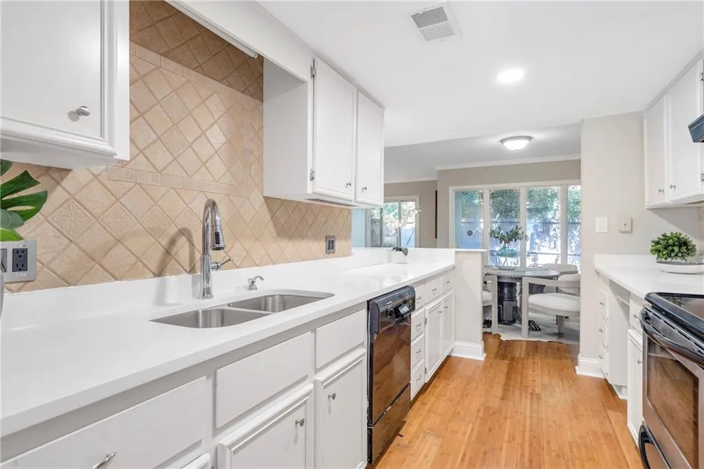 Kitchen with dishwasher, stainless steel electric range, tasteful backsplash, white cabinetry, and ornamental molding