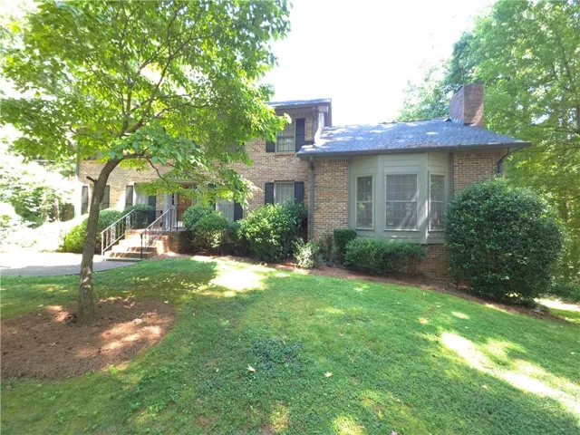 4 sided brick exterior featuring a bay window, established landscaping, and a front entry with handrails