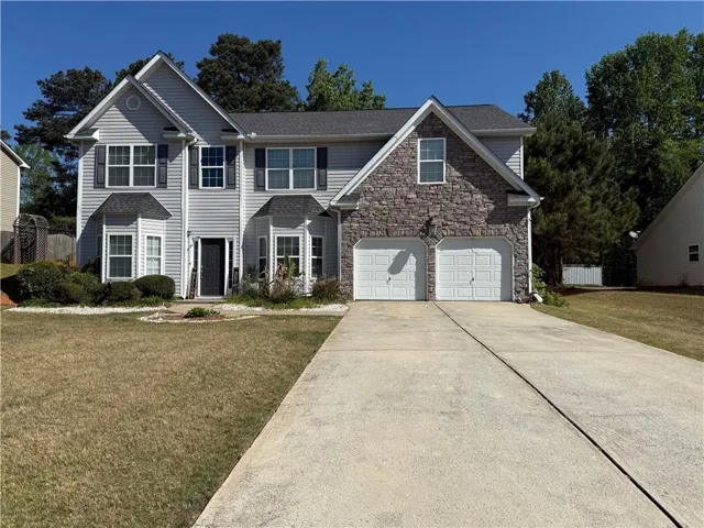 Traditional-style home featuring driveway and stone siding