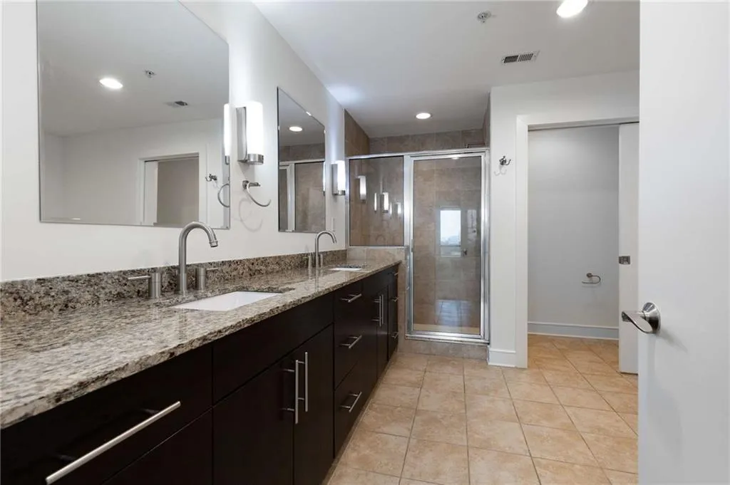 Full bathroom featuring tile patterned floors, visible vents, double vanity, and a sink