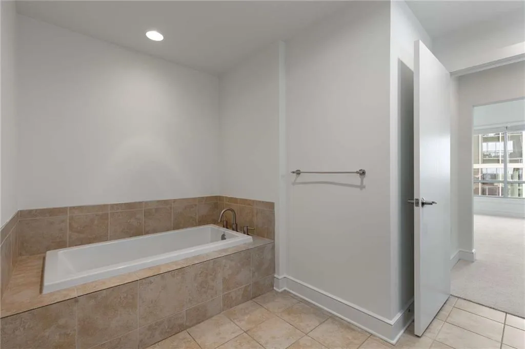 Bathroom with recessed lighting, tile patterned floors, baseboards, and a bath