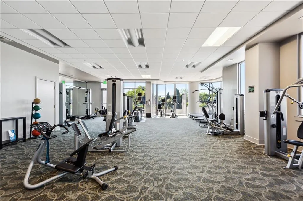 Gym featuring a paneled ceiling, carpet flooring, and baseboards