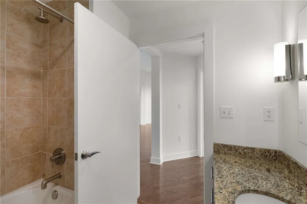 Bathroom with bathing tub / shower combination, wood finished floors, and baseboards