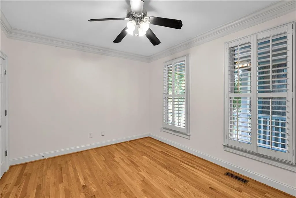 Hardwood flooring, crown molding, ceiling fan, and plantation shutters