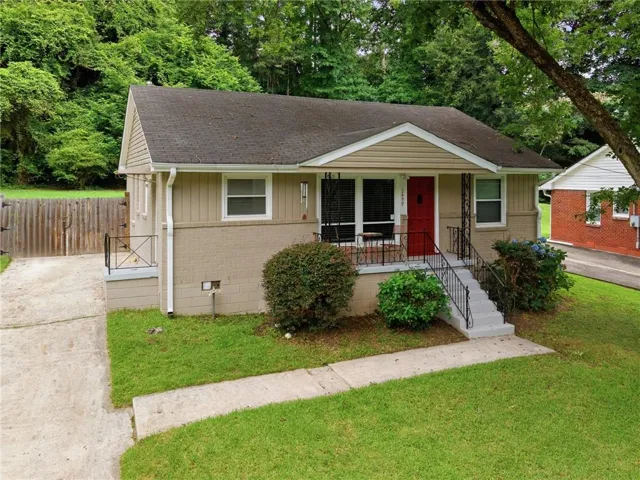 Front exterior with a covered porch, red entry door, and a paved driveway