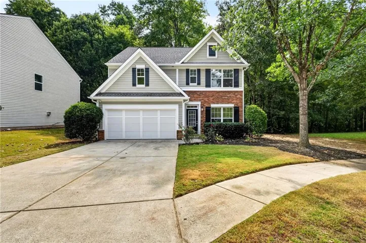 Two-story residence featuring a brick and siding facade, a two-car garage, and a concrete driveway