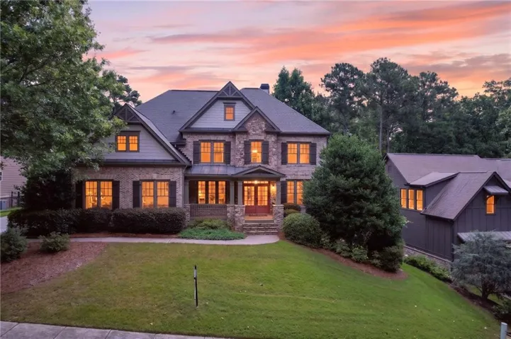 Elegant two-story Colonial residence showcasing a brick exterior, multiple gabled rooflines, and illuminated windows