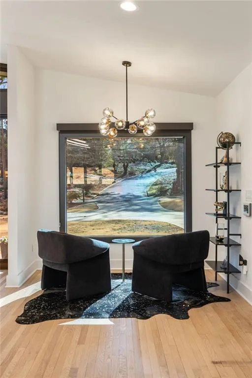 Hardwood flooring, recessed ceiling lighting, a modern chandelier, and a large picture window with dark trim