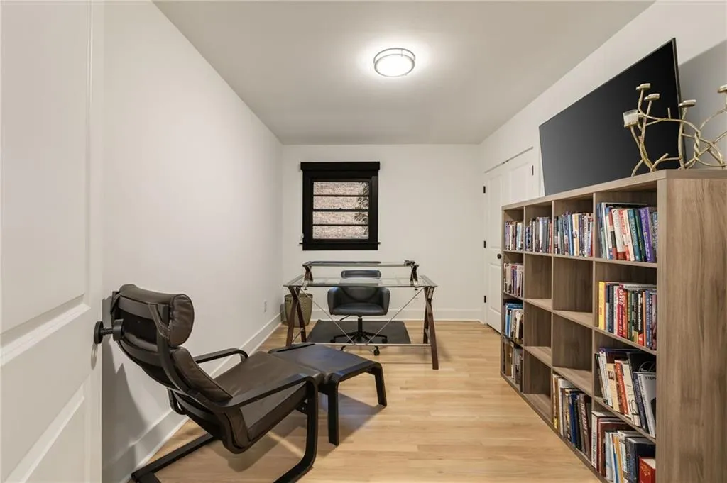Light wood-finish flooring, built-in shelving, white walls, and a ceiling-mounted light fixture