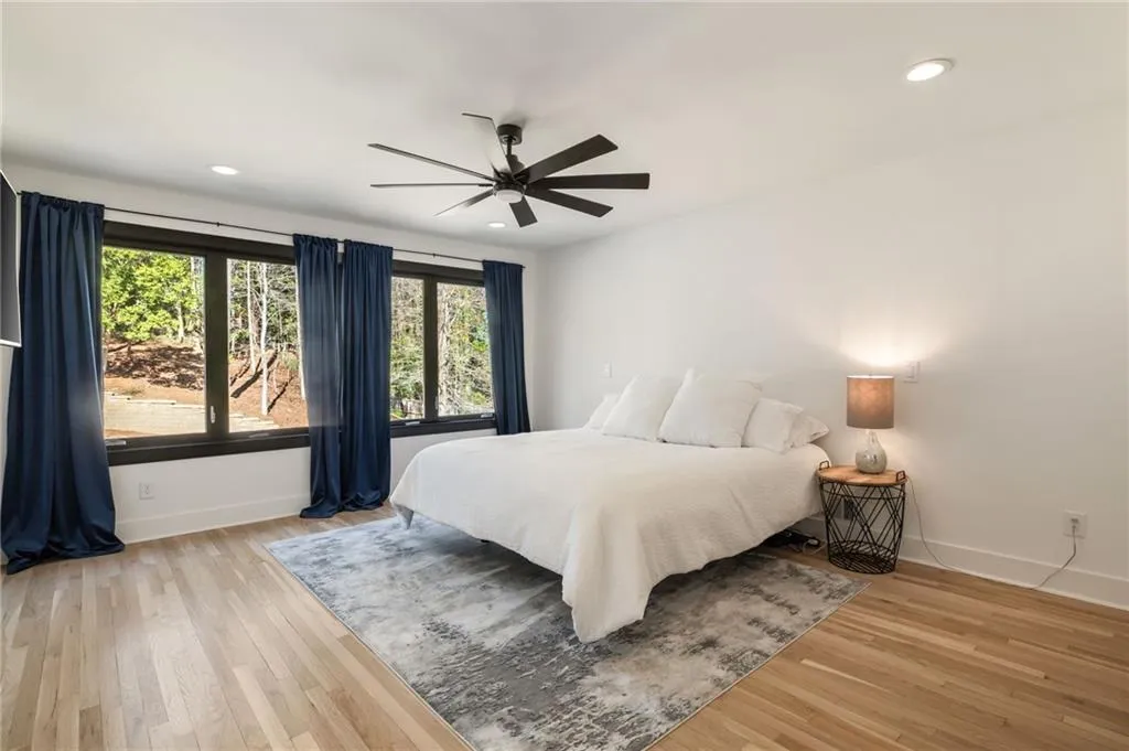 Recessed ceiling lighting, wood-finish flooring, ceiling fan, and multiple large windows with dark trim