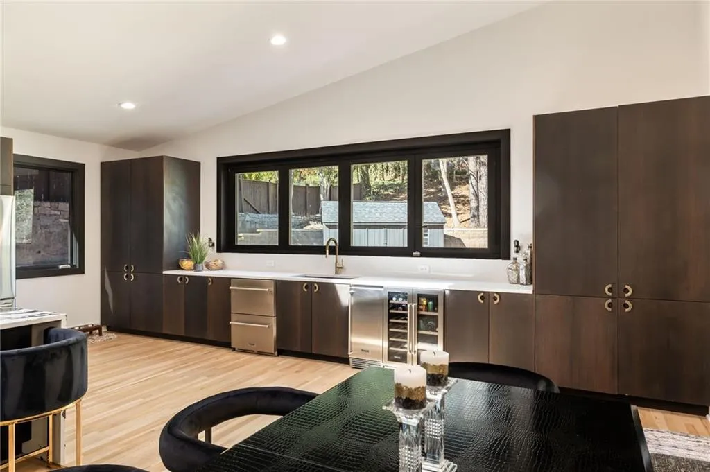 Vaulted ceiling with recessed lighting, full-height dark wood cabinetry, white countertops, built-in beverage refrigerator, and light wood-finish flooring