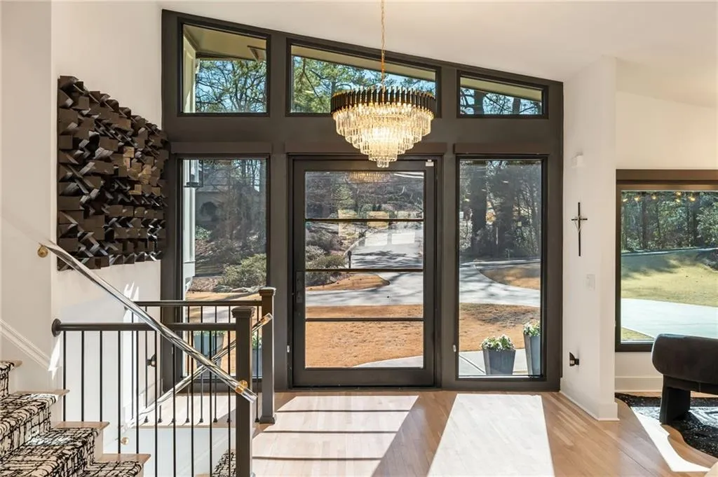 Double-height entryway with a contemporary chandelier and light wood-finish flooring