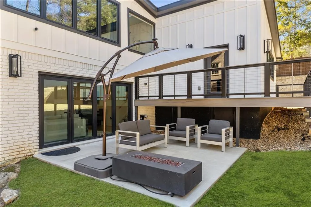 Outdoor concrete patio with a modern fire pit, leading to a white brick and vertical siding exterior