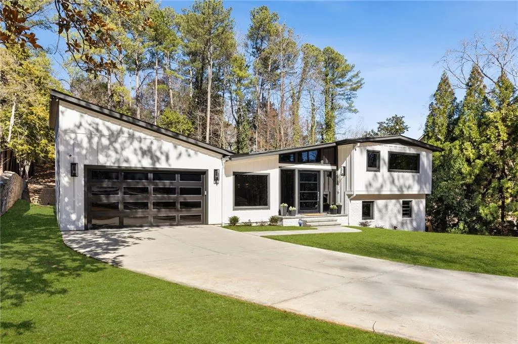 Modern architectural design with a sloped roofline, attached two-car garage with frosted glass panels, and a concrete driveway