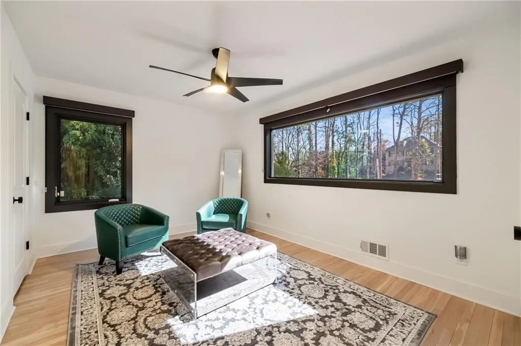 Hardwood flooring, expansive horizontal window, modern ceiling fan with lighting, white walls, and dark window trim