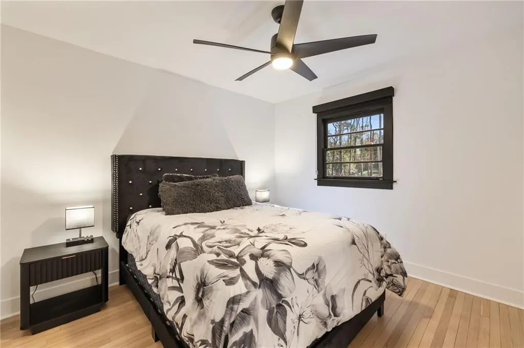Wood-finish flooring, black window trim, and a ceiling fan with integrated lighting