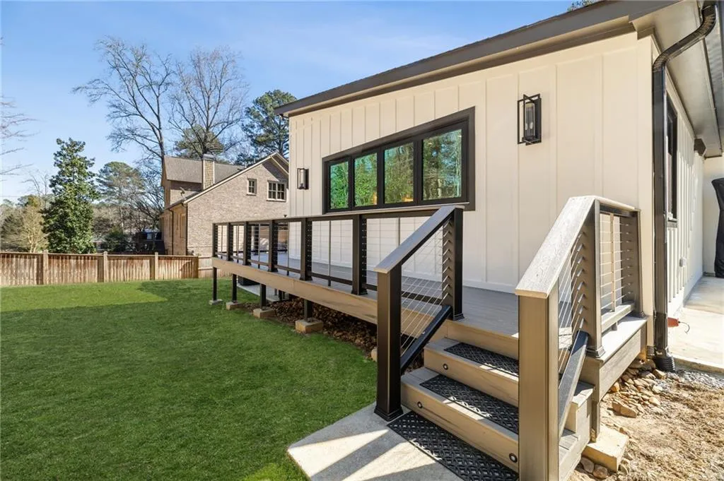 Exterior featuring vertical white siding, black-framed windows, and an elevated composite deck with cable railings
