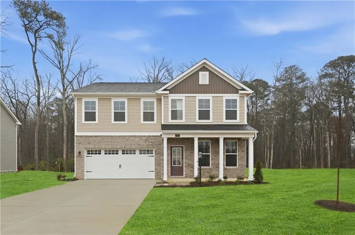 Two-story residence featuring a two-car garage, brick and siding exterior, covered entry, and a prominent front door