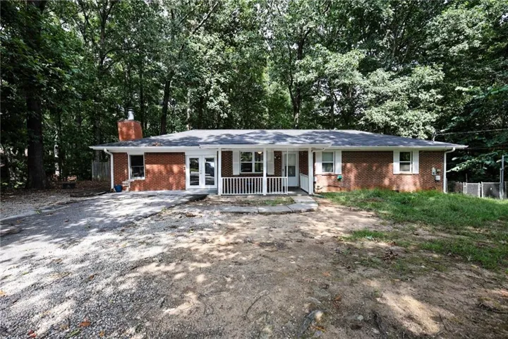 Brick-front exterior with a white porch railing, white porch columns, white window shutters, and a dark roof