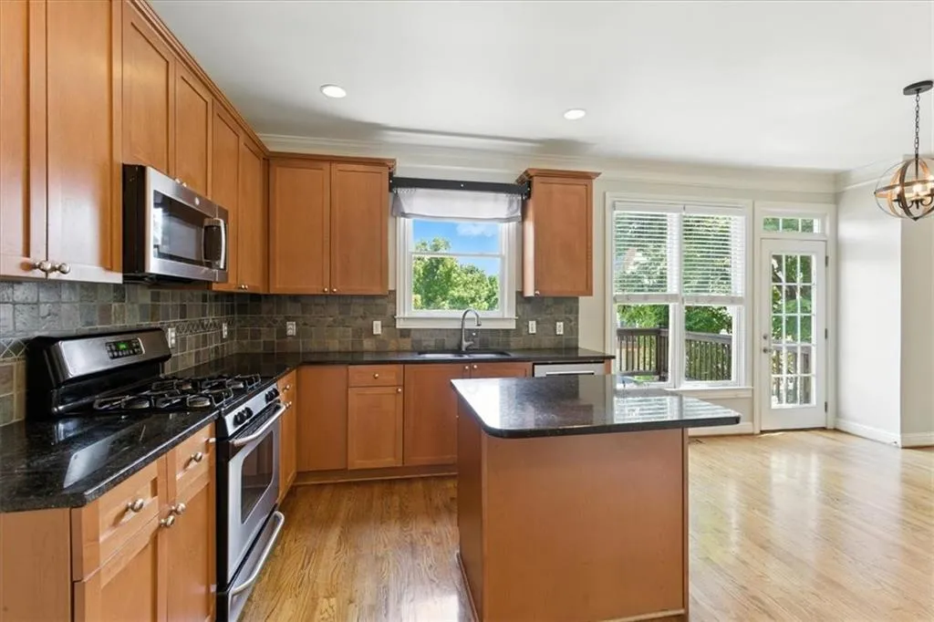 Kitchen with appliances with stainless steel finishes, crown molding, backsplash, light wood-style floors, and a kitchen island