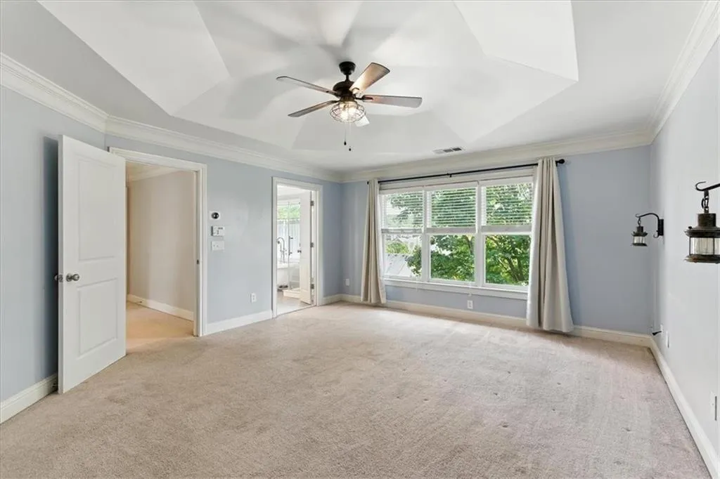 Carpeted empty room with crown molding and ceiling fan